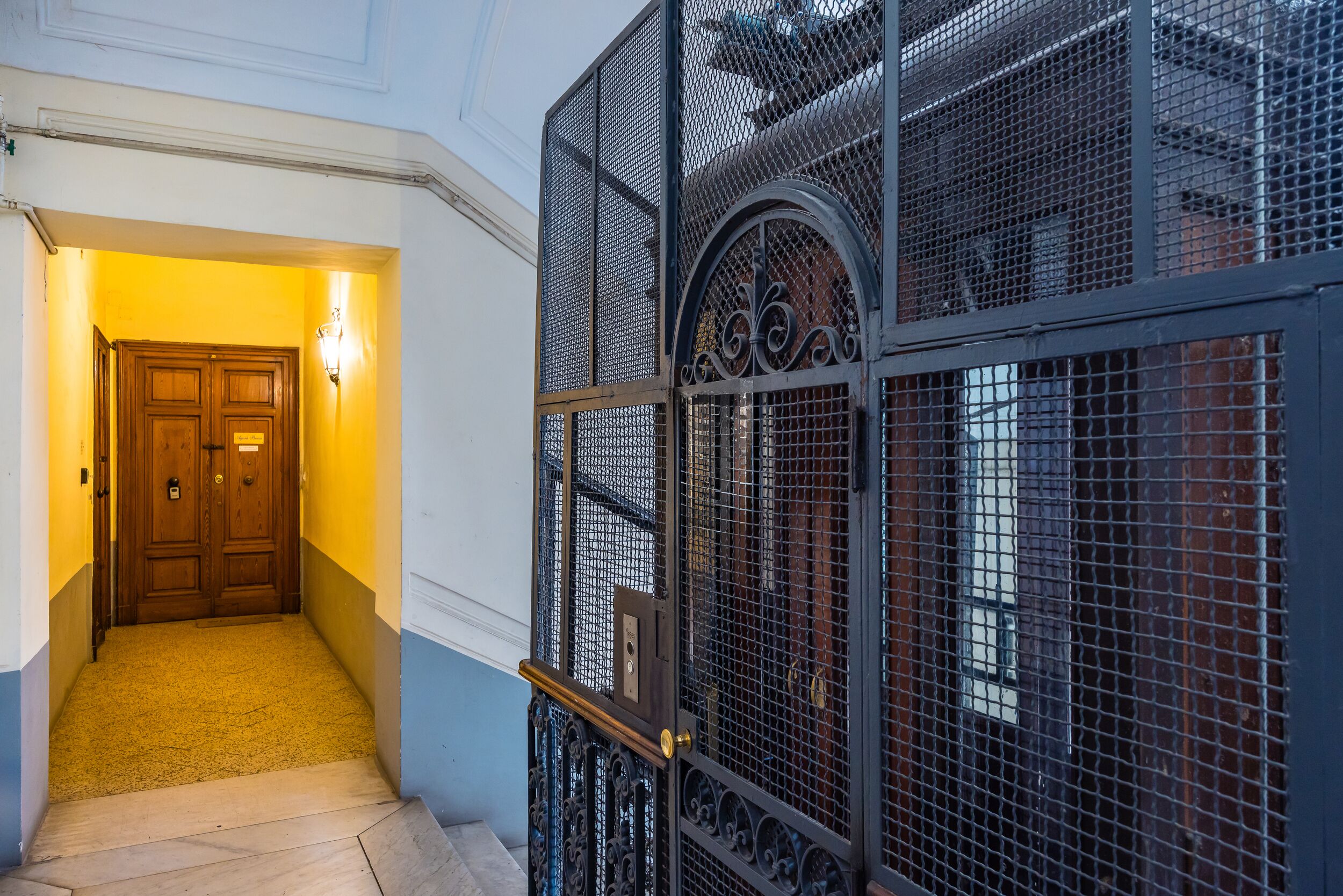 A hallway with a wooden door labeled 'Guest Room' and a metal gate with decorative elements.
