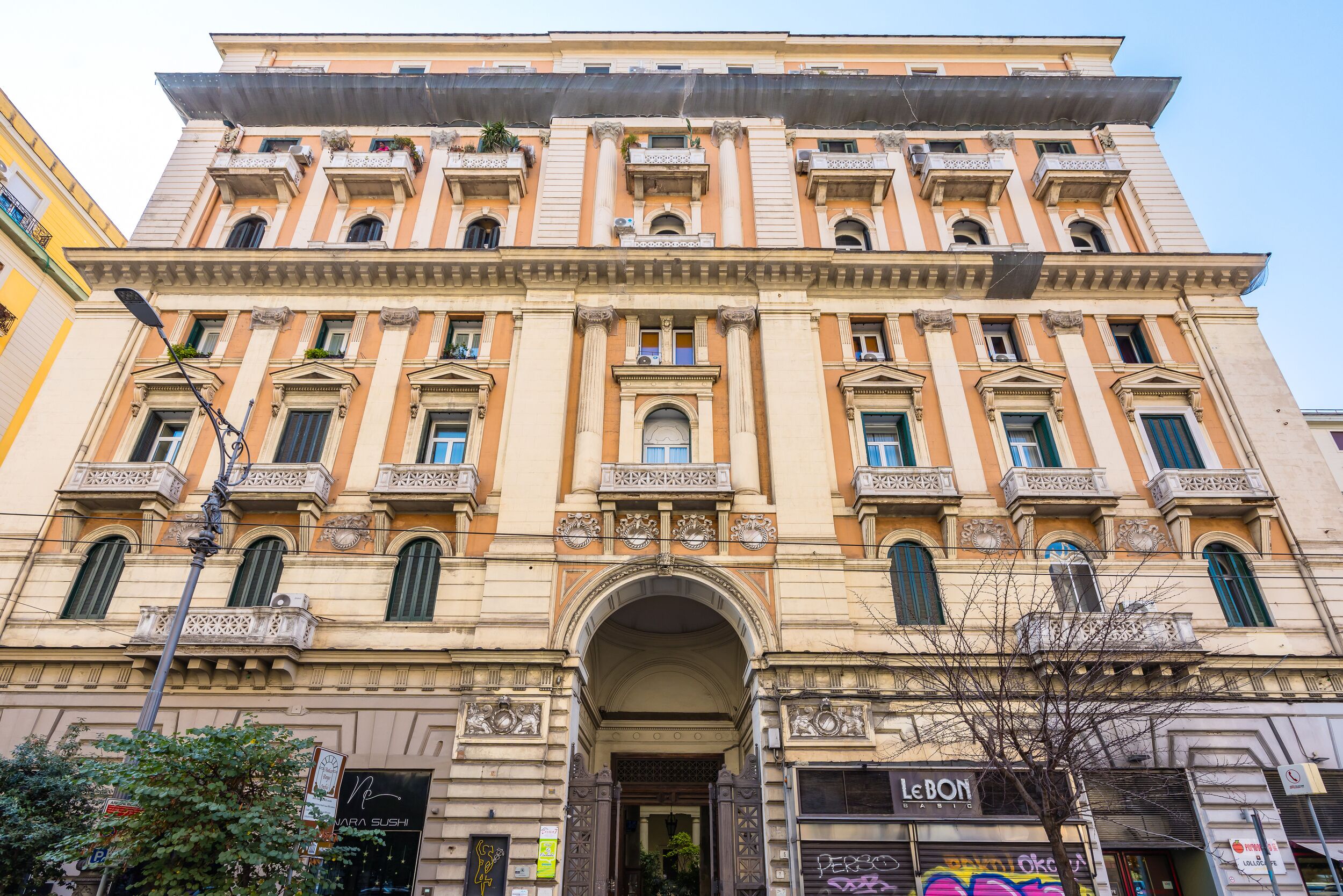 A historic building with a central entrance, multiple balconies, and a ground-level storefront.