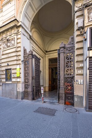 An ornate entrance with a large archway and decorative metal gates. - Agorà Borsa (Naples)