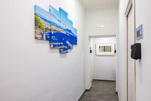 A hallway with a large painting of a coastal cityscape. - Agorà Borsa (Naples)