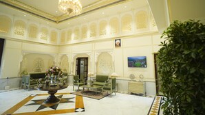 A lobby with a chandelier, seating area, and a television on the wall. - Anant Mahal Jaipur (Jaipur)