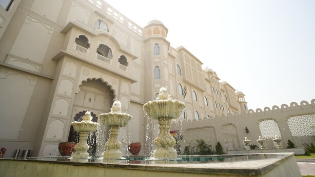 A large building with ornate architecture, including arched windows and balconies, and a fountain in the foreground. - Anant Mahal Jaipur (Jaipur)