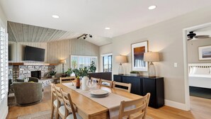 A dining area with a wooden table, chairs, a fireplace, and a television mounted on the wall.