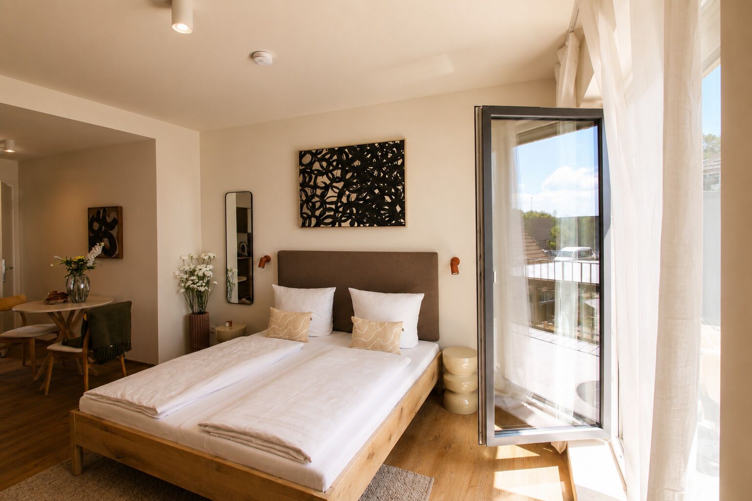 Een moderne slaapkamer met een groot bed, een bureau en een balkon met een glazen deur.