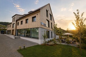 A modern building with a wooden facade, large windows, and a sign indicating it is a hotel. - homie stay am sonnenstuhl (Randersacker)