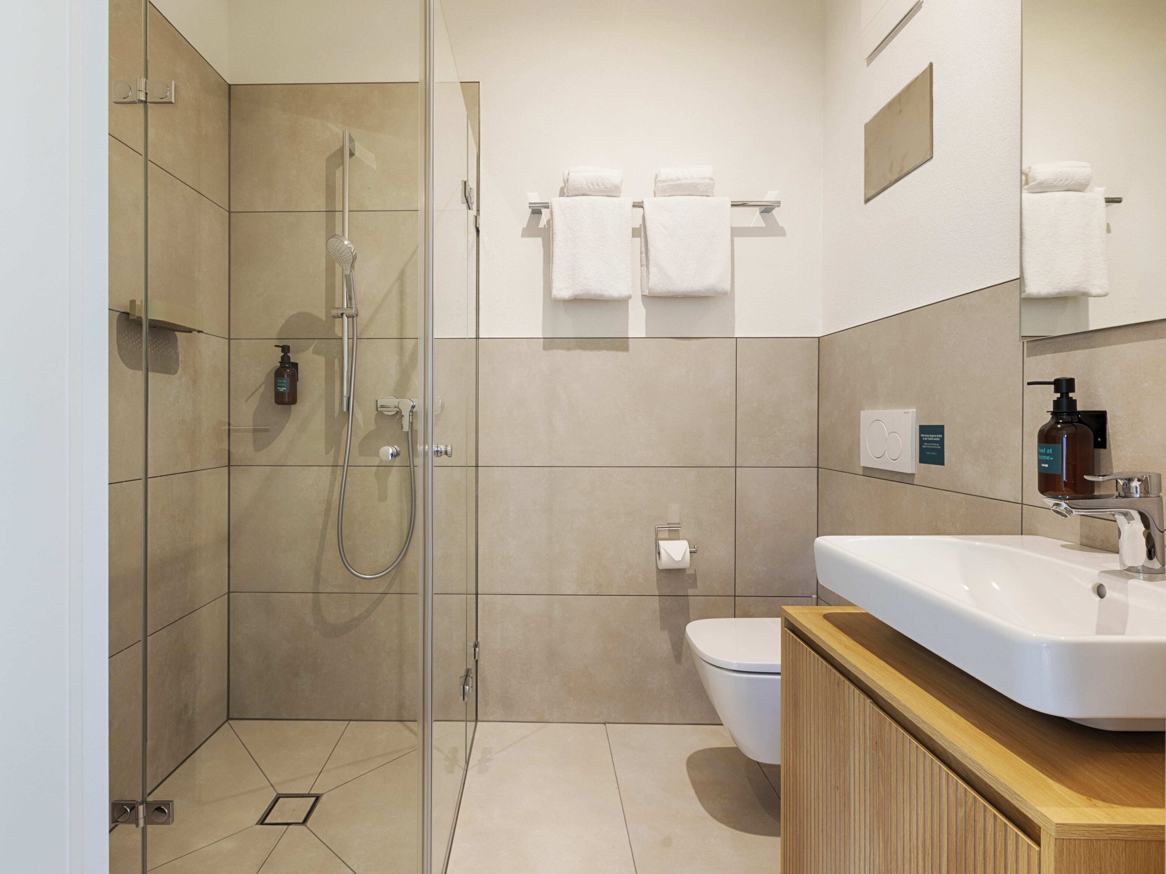 A modern bathroom with a glass-enclosed shower, a white sink, and a toilet.