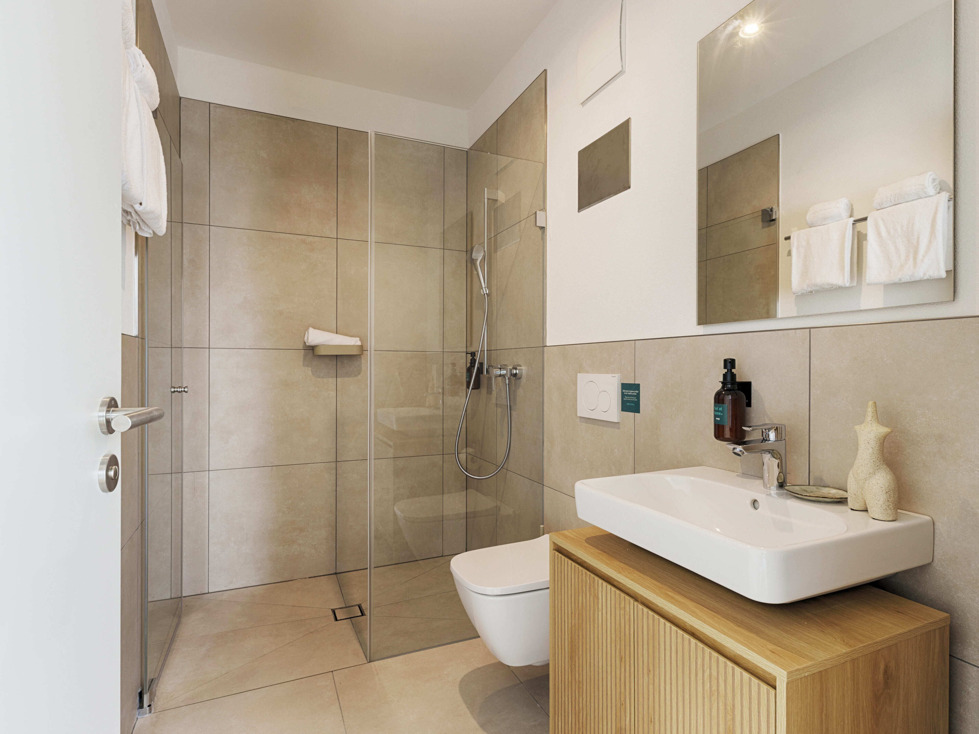 Ein modernes Badezimmer mit einer Duschkabine aus Glas, einer weißen Toilette und einem Holzwaschtisch mit Waschbecken.