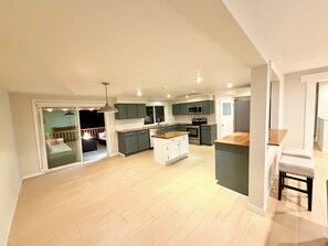 A spacious kitchen with modern appliances, a dining area, and a balcony. - Ultimate Oasis-Waterpark, FIFA!, Games & Huge Yard (Langley Township)