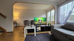Ein Wohnzimmer mit Fernseher, Sofa und einer Treppe.