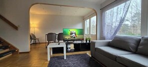Ett vardagsrum med en TV, en soffa och en trappa.