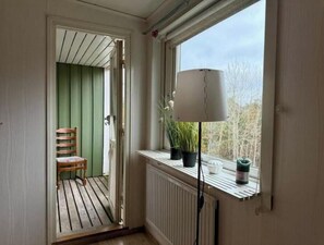 Ett rum med ett fönster, ett element, en stol och en krukväxt.