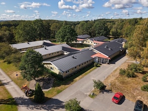 A residential area with multiple houses, a paved driveway, and a red car parked on the street. - Ekängens vandrarhem (Virserum)