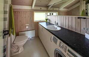 A compact bathroom with a toilet, sink, and washing machine. - Cozy home in Strandby with sauna (Strandby)
