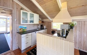 Une cuisine compacte avec des meubles blancs, un plan de travail noir et un petit îlot central doté d’un évier.