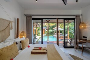 Une chambre dotée d’un grand lit, d’un bureau et offrant une vue sur une piscine et un espace de détente extérieur.