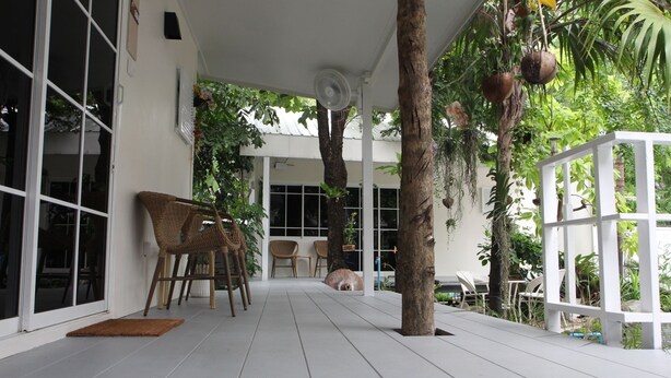 A covered outdoor area with a white floor, wicker chairs, and a table. - Homeku Guesthouse Room 4 Cozy Stay Close to Suvarnabhumi Airport (Lat Krabang)