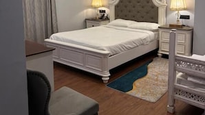 A bedroom with a large bed, two bedside tables with lamps, a desk, a chair, and a chandelier. - Hotel Tuli Grand Imperial (Nagpur)