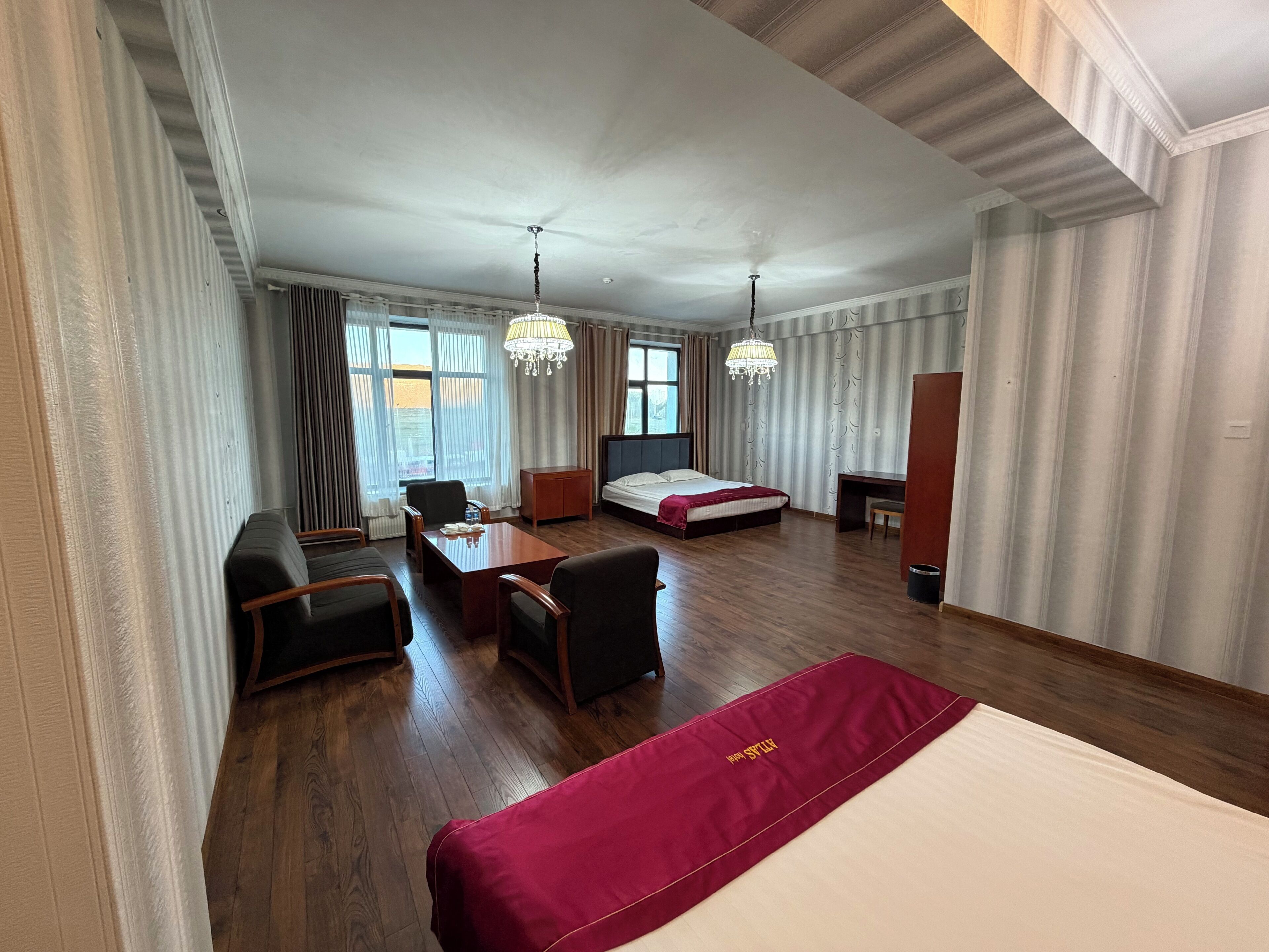 A hotel room with a bed, desk, chair, and a dining table.