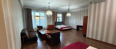 A hotel room with a bed, desk, chair, and a dining table.