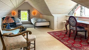 Quarto de sótão acolhedor com duas camas, uma escrivaninha e uma cadeira.