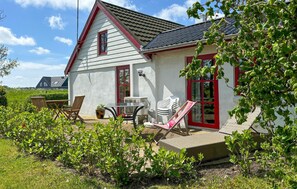 A house with a sloped roof, a red door, and a small patio with outdoor furniture. - Beautiful home in Thisted with house sea view (Thisted)
