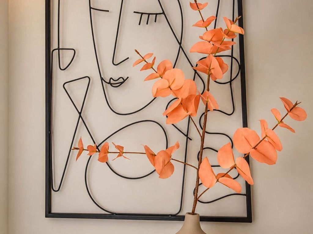 A framed abstract artwork with a vase of orange flowers.