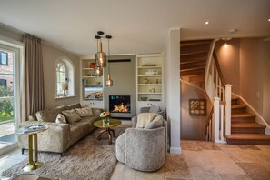 Ein Wohnzimmer mit Kamin, einer Treppe und Blick ins Freie.