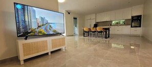 Ein modernes Wohnzimmer mit Flachbildfernseher, einem Essbereich und einer Küche.