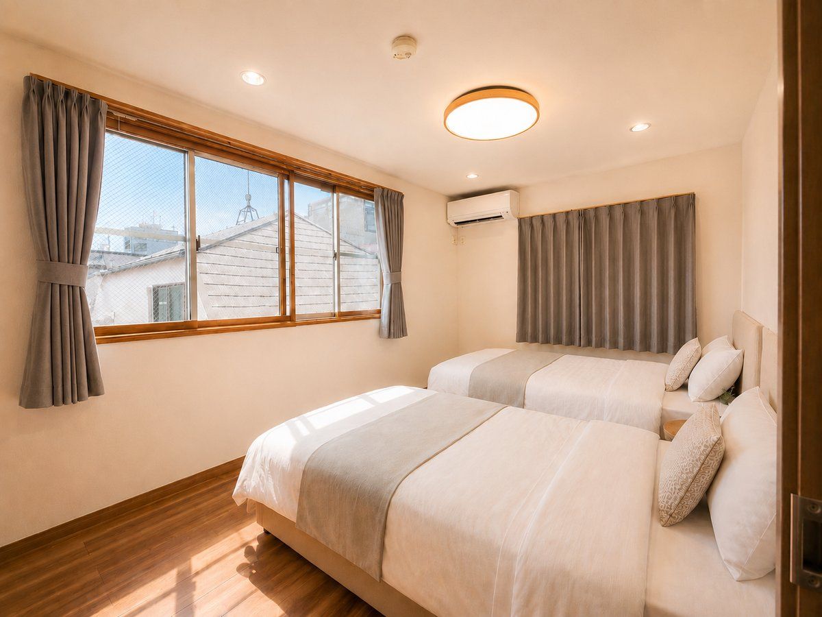 A hotel room with two beds, a window with curtains, an air conditioning unit, and a wooden floor.