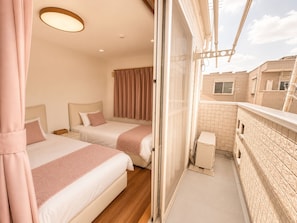 A hotel room with two beds, a balcony, and a view of the cityscape.