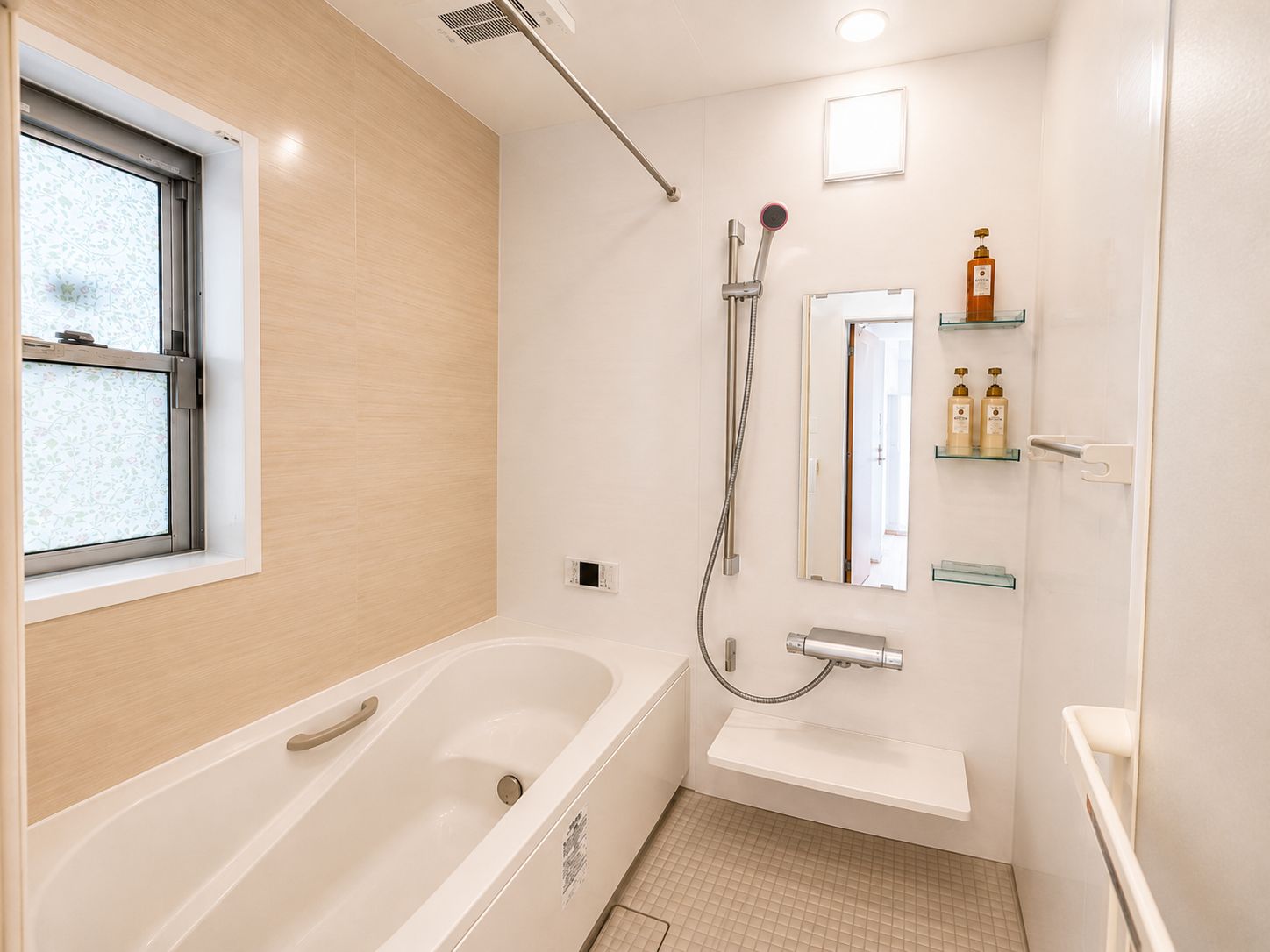 A modern bathroom with a bathtub, a shower, and a toilet. There is a window on the left, and a shelf with toiletries on the right.
