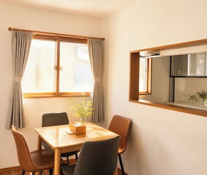 A dining area with a table, chairs, and a window with curtains.