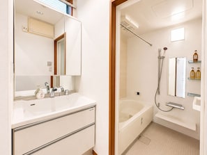 A modern bathroom with a white sink, mirror, and a separate shower area.