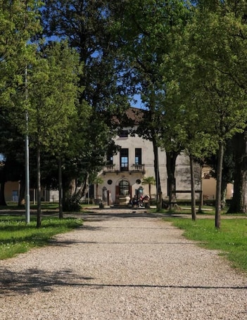 A pathway leading to a building with a symmetrical facade, arched windows, and a central entrance.. Guesthouse Villa Fabris