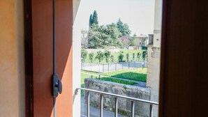 A balcony with a view of a green park, a fence, and buildings in the background. - Guesthouse Villa Fabris (Thiene)