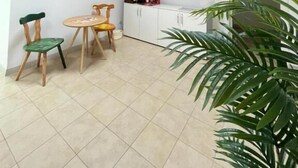 A room with a sloped ceiling, a skylight, a dining area with chairs and a table, a kitchen area with cabinets, and a large potted plant. - Guesthouse Villa Fabris (Thiene)