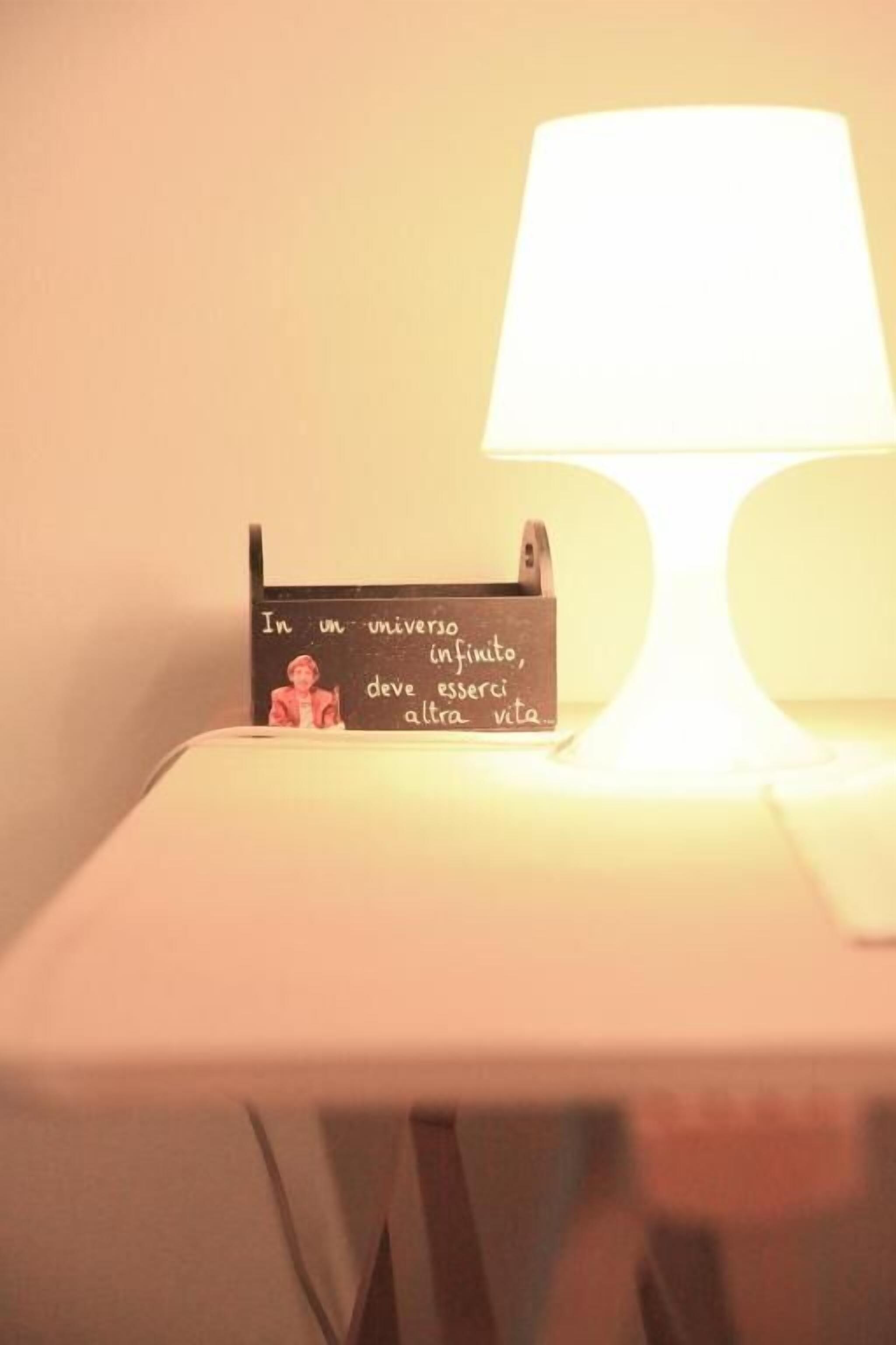 A bedside table with a lamp and a sign with text.
