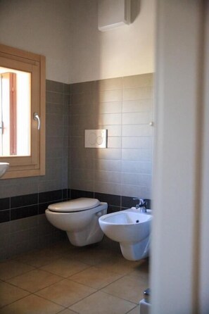 Een badkamer met toilet, hygiëneschuimer en wastafel.