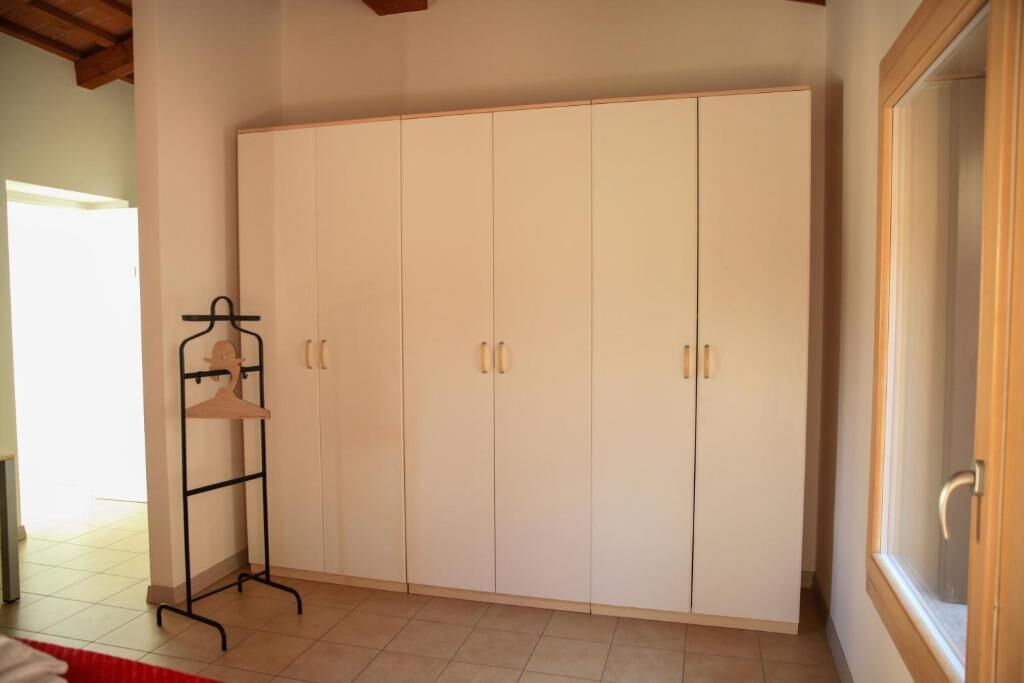 A room with a large wardrobe, a coat rack, and a window.