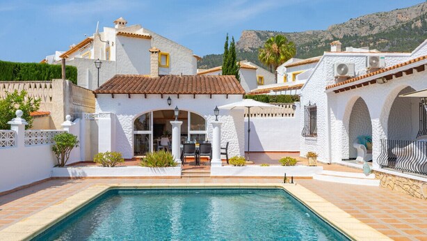 A poolside area with a pool, white buildings, and a mountainous backdrop. - Villa Dalia - Plusholidays (Calpe / Calp)
