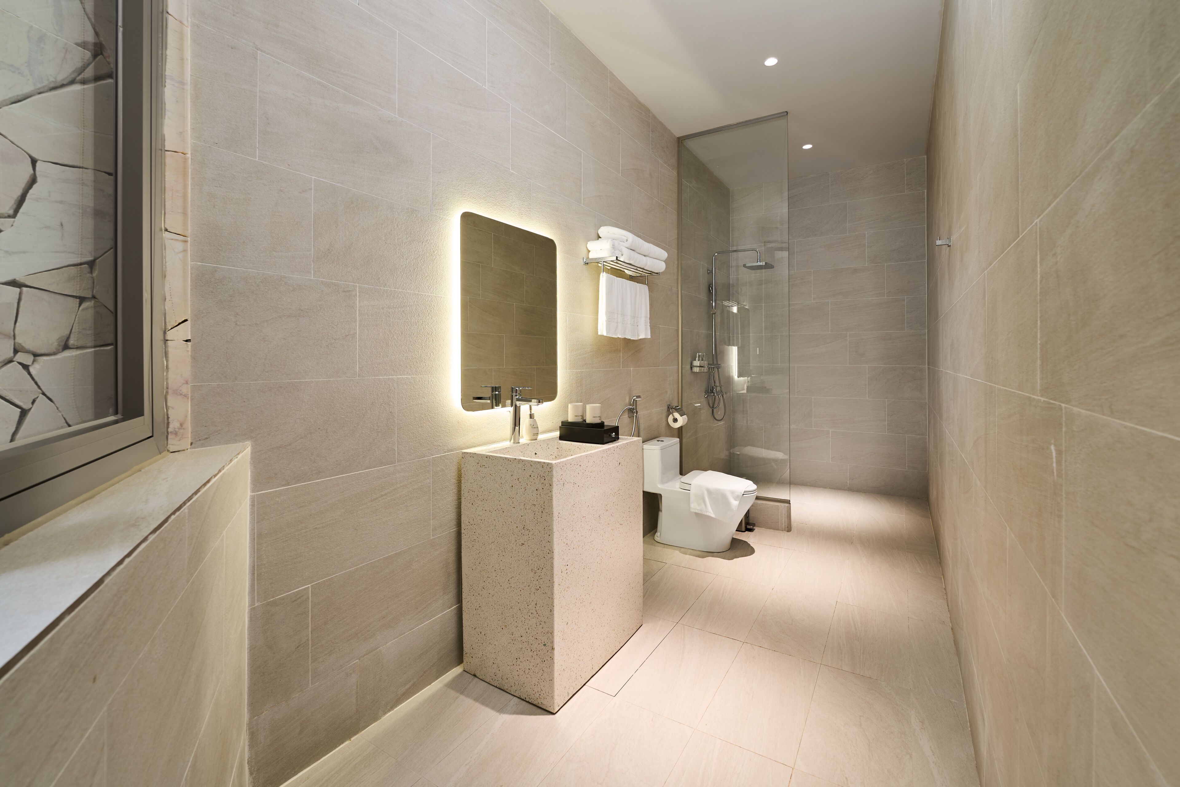 A modern bathroom with a large mirror, a freestanding sink, a toilet, and a glass-enclosed shower.