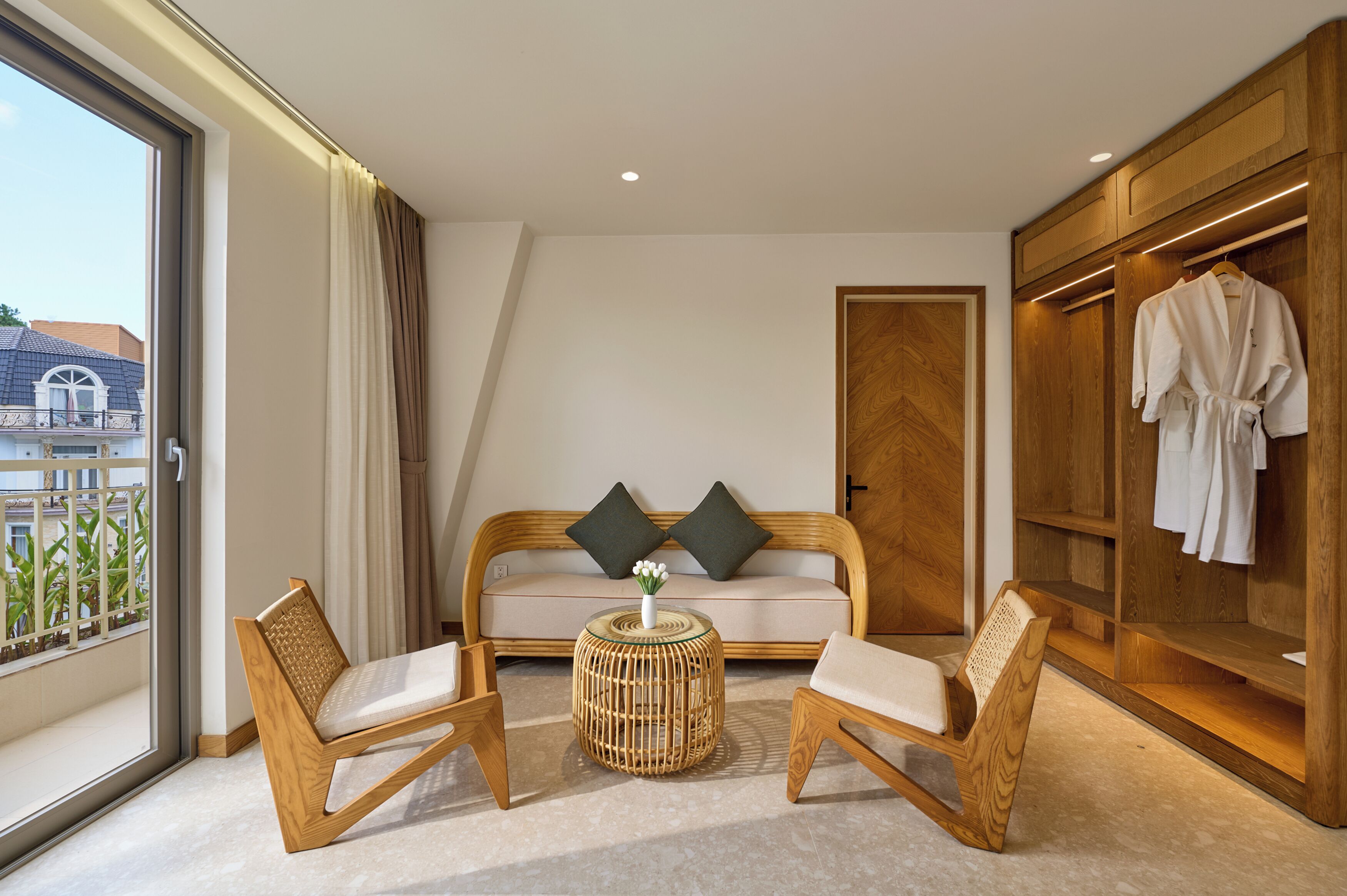 A hotel room with a sofa, two chairs, a small table, and a wardrobe.