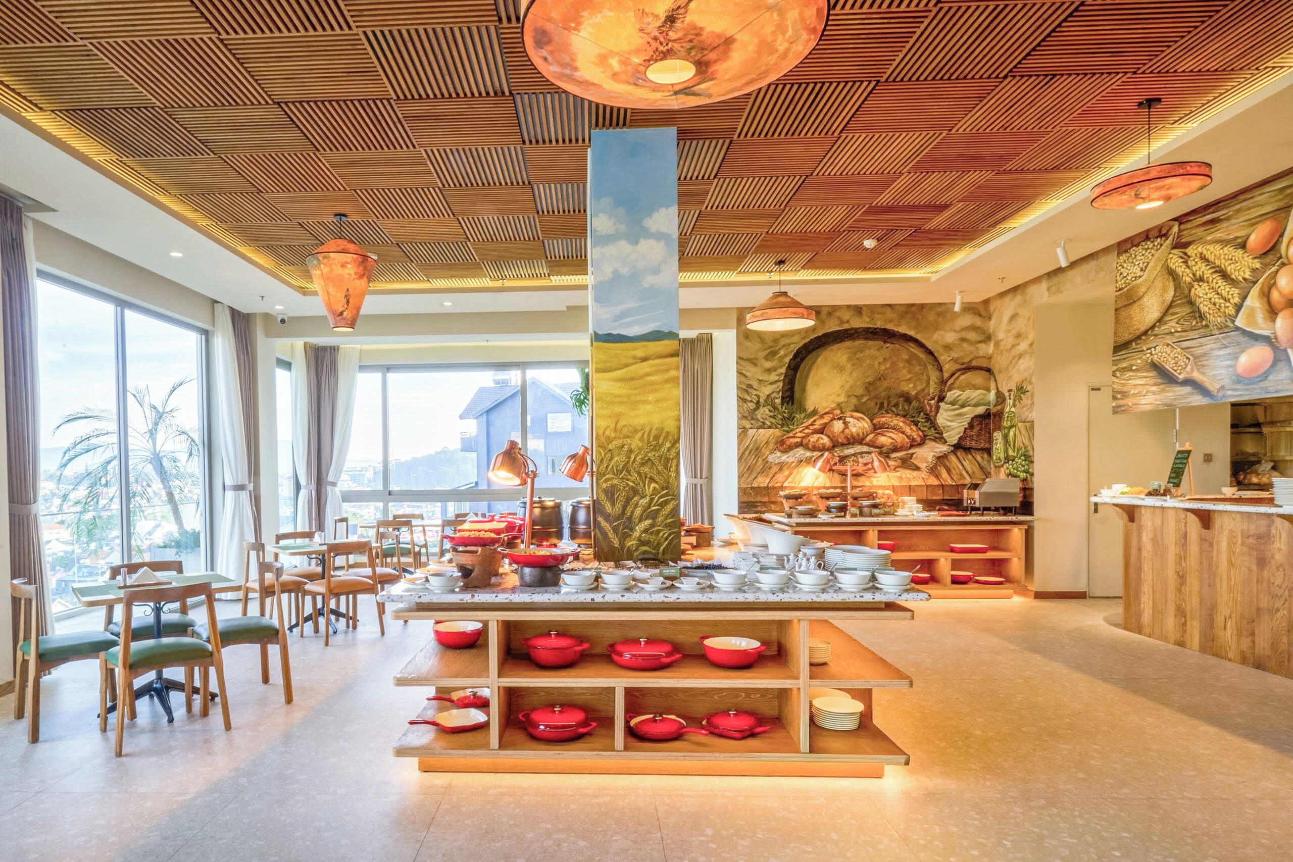 A restaurant with a wooden ceiling, large windows, and a central serving area with red bowls.