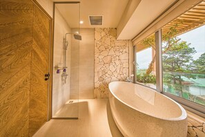 Une salle de bain moderne avec une baignoire sur pieds, une douche à parois de verre et un mur d’accent en pierre.
