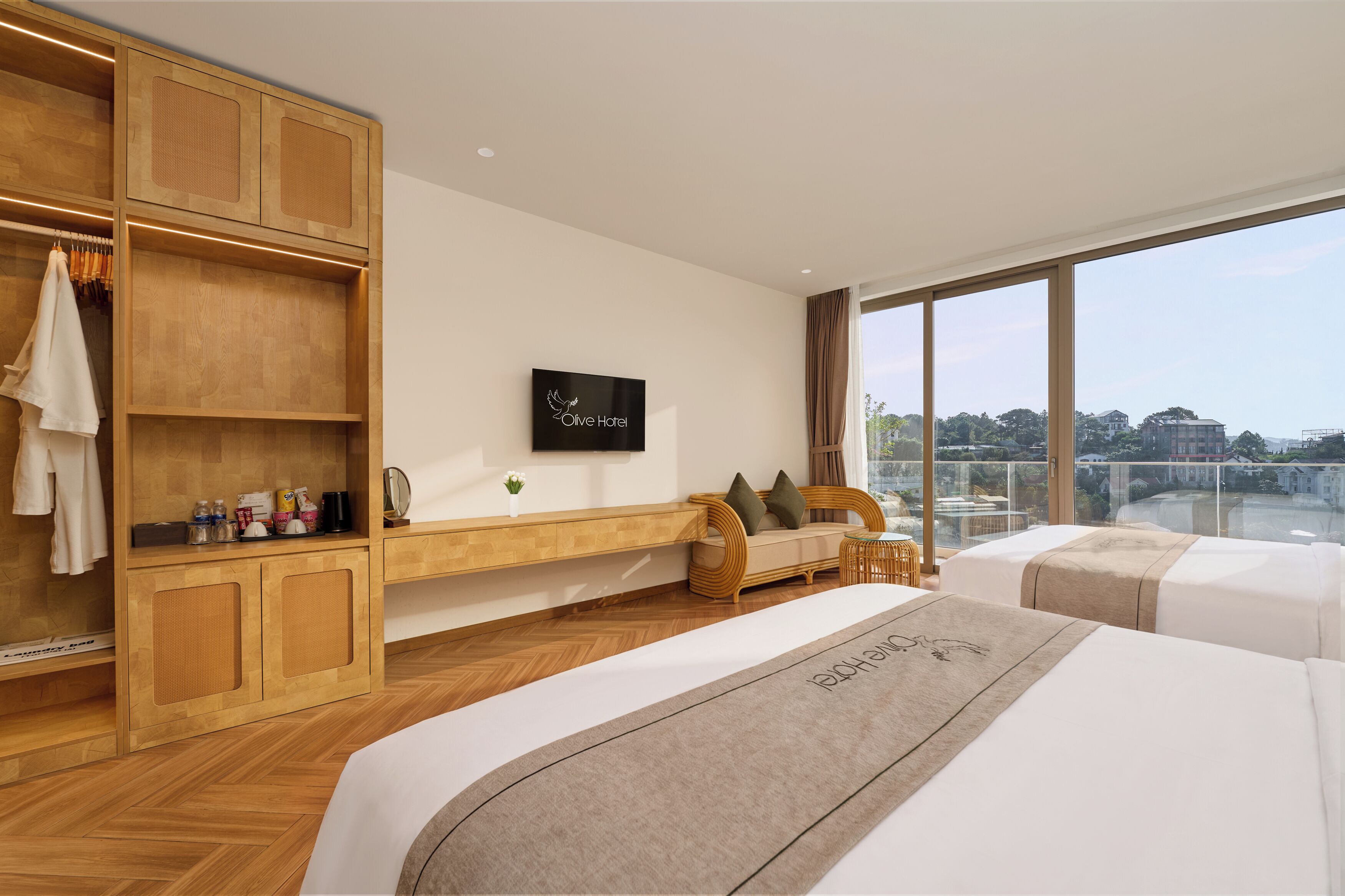 A hotel room with a large window, a wooden wardrobe, a sofa, and two beds.