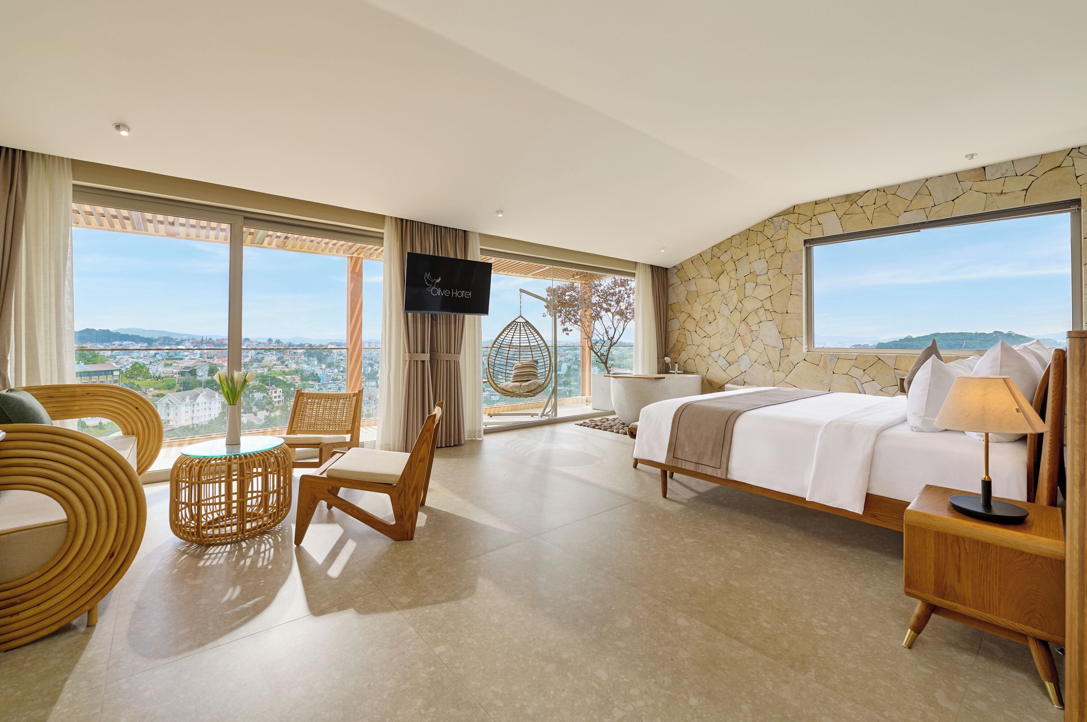 A hotel room with a bed, a TV, a chair, and a view of the city.