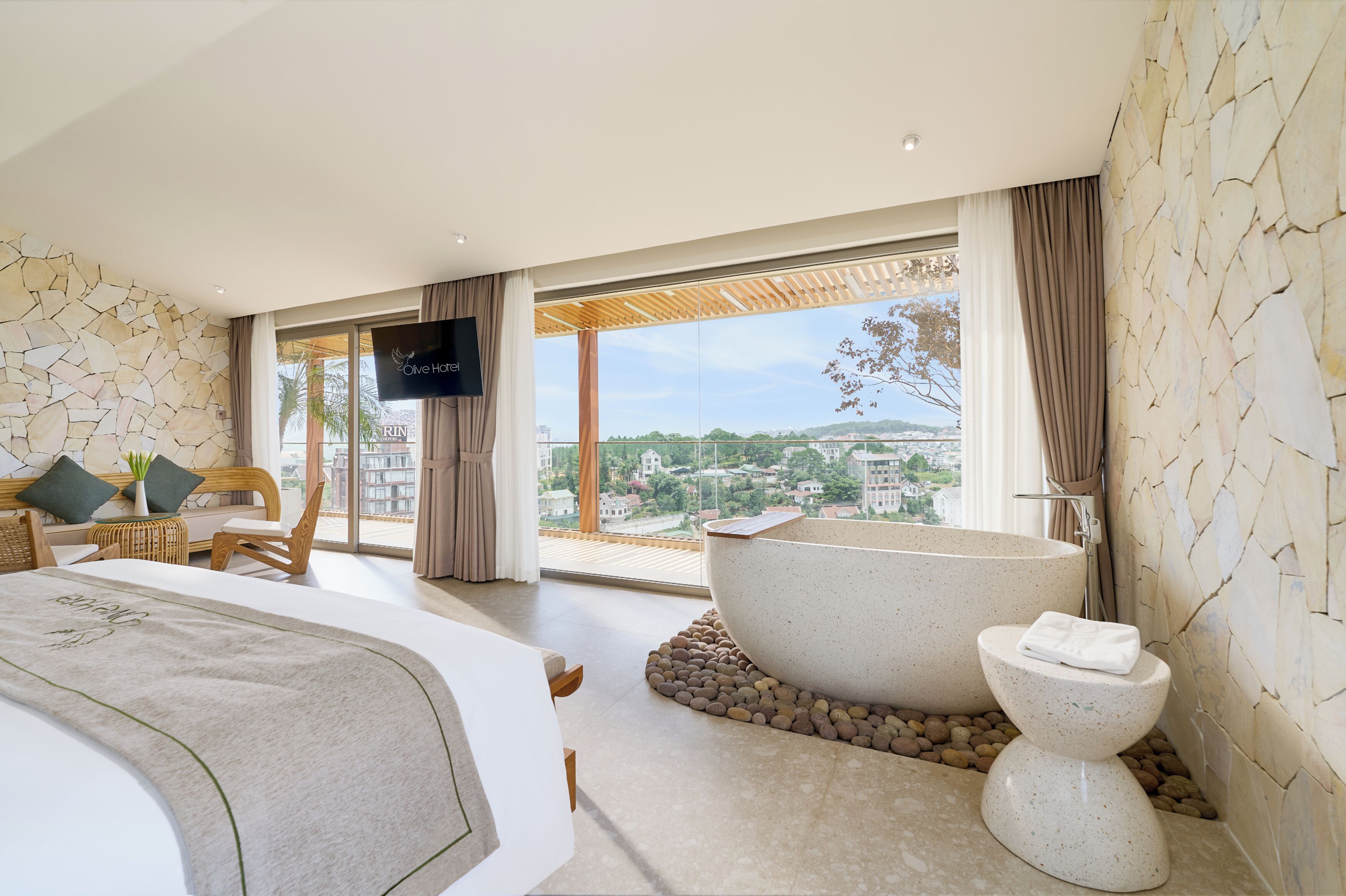 A modern bedroom with a large bed, a bathtub, and a view of the city.