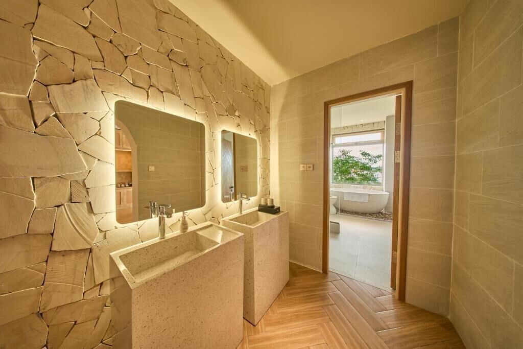 Un baño con pared de piedra, dos lavamanos y un espejo.