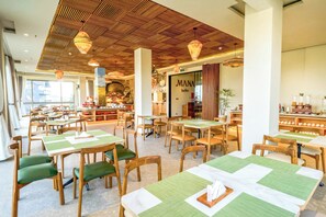 A restaurant with wooden tables and chairs, a buffet area, and a view of the outside.