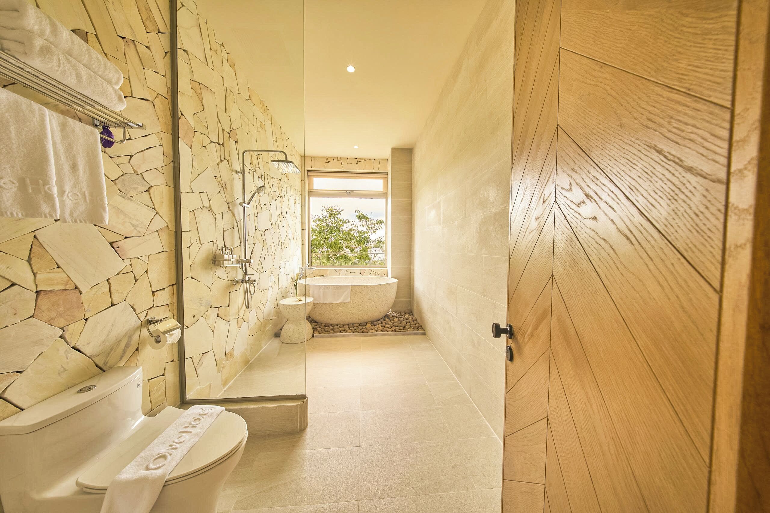 Un baño con pared de piedra, bañera y retrete.